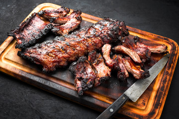 Barbecue pork spare loin ribs St Louis cut with hot honey chili marinade burnt as closeup on a wooden cutting board
