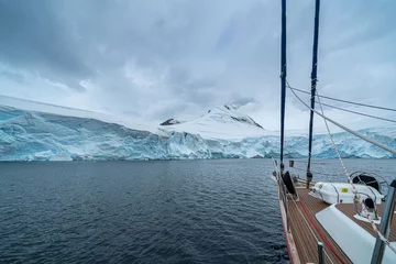 Gordijnen sailing boat in Antarctica, yacht navigation through icebergs and sea ice © suvorovalex