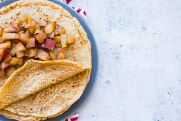 Sweet delicious crepes or thin pancakes stuffed with baked tasty apples filling inside. Homemade vegan food dessert. Copy space