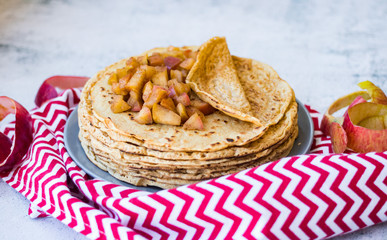 Sweet delicious crepes or thin pancakes stuffed with baked tasty apples filling inside. Homemade vegan food dessert.