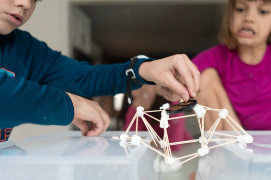 Children building a suspension bridge of out marshmallows and toothpicks for a STEAM lesson