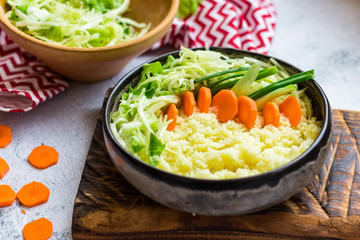 Couscous wheat durum millet tabbouleh in bowl with greens and vegetables.