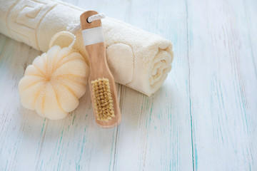 Fototapeta na wymiar Beautiful spa concept. Towel, body brush and washcloth on a light wooden background with space for copy space. Beauty background