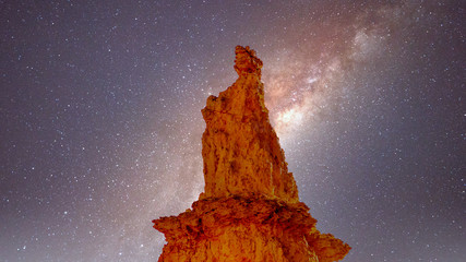 Galaxy in the night sky over the natural statue of Queen Victoria created by erosion of a Sandstone Pinnacle in the Queen's Garden part of Bryce Canyon National Park, Utah, United States