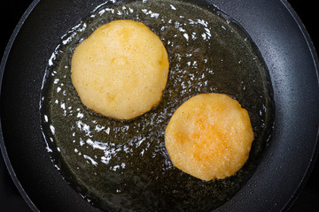 Arepas in a pan with oil. Top view. Cooking Venezuelan food.