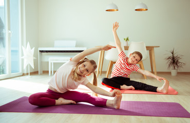 Happy children making yoga at home dueing coronavirus quarantine