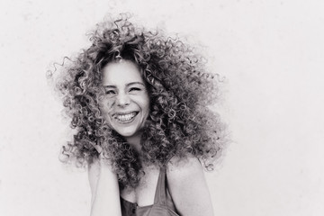 Cute curly blonde with afro hairstyle laughs. plain gray background. emotional photo black and...
