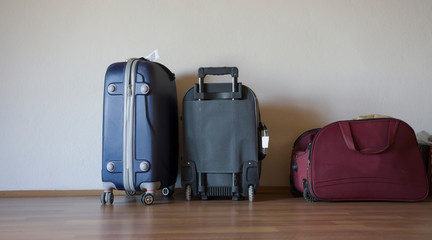 Empty room with suitcases ready for house moving concept. Packed household stuff for moving into new house / new home. Boring preparation process for new city or new country. Line up baggages / cases.