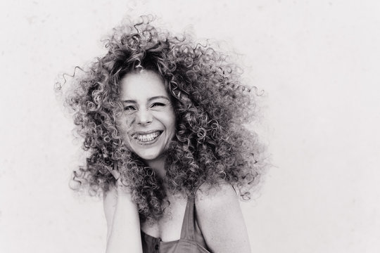 Cute curly blonde with afro hairstyle laughs. plain gray background. emotional photo black and white photo 