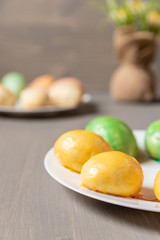 gefüllte bunte Ostereier aus Hefe mit Zuckerguss auf grauem Grund aus Holz für die Feiertage zum Kaffee