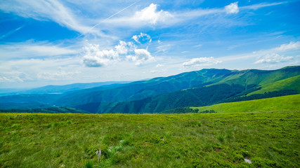 sunny afternoon. wonderful springtime landscape in mountains. grassy field and rolling hills. rural scenery. On a background of blue mountains. green alpine mountains covered with green grass. spring