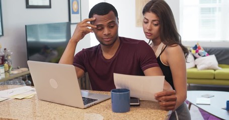 Millennial couple sitting at kitchen counter looking over student loan bills. Young newlywed homeowners planning budget over breakfast. Man and woman in debt. 4k slow motion handheld