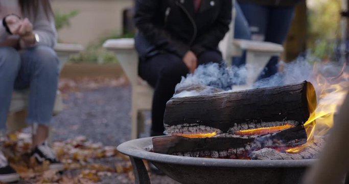 Family gathers around bon fire in autumn day - close up on burning logs