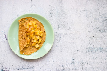 Homemade golden crepes or thin pancakes stuffed with sweet cooked apples. Vegan dessert.