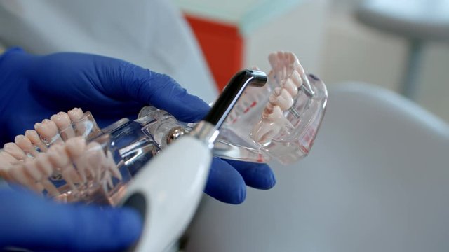 a dentist checking a model of artificial teeth in a laboratory and using polymerization tool with bright blue light