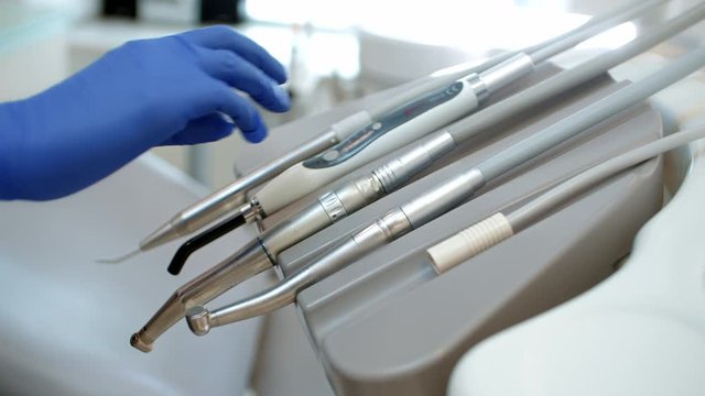 a dentist takes a tool from the unit console in a brightly lit laboratory