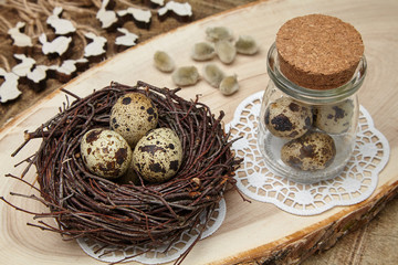 Bird eggs in a nest, eggs in a jar, wooden hares and willow buds on a wooden saw. Easter concept