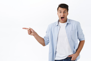 Portrait of amazed handsome caucasian man react impressed and wondered at new awesome product in...
