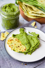 Green chickpea hummus with spinach and parsley in glass jar and flatbread tortillas, chapati or pita bread. Vegan lunch or vegetarian dinner. Healthy food.