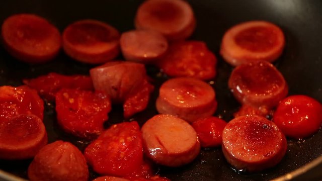 Making an amlet breakfast with tomatoes and sausages.