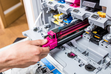 Man repairs color printer in the office. Color cartridge replacement