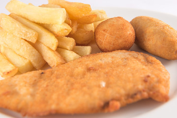Plate of breaded chicken breast with croquettes and French fries.