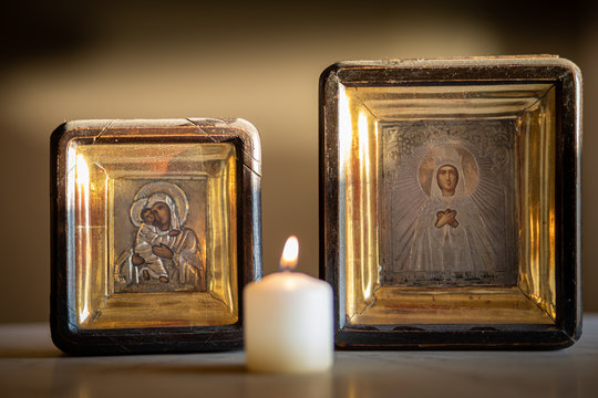 A candle burning in front of an icon of holy mother and child