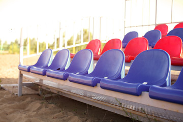 Empty Volleyball court at the city beach. Nobody is on the summer beach due to quarantine infection. Outdoor sports competition. Close up view of plastic chairs on the stadium bench.
