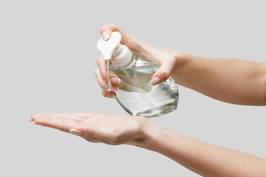 Female hands using hand sanitizer gel or liquid soap dispenser over light grey background