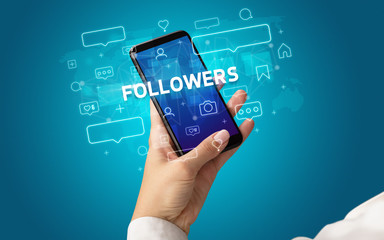 Female hand typing on smartphone with FOLLOWERS inscription, social media concept