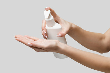 Female hands using hand sanitizer gel or liquid soap dispenser over light grey background