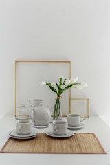White tulips in a glass vase on a white table. In a light interior in a Scandinavian style, minimalism.