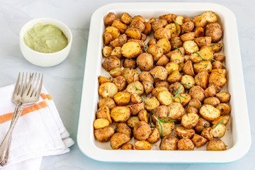Roasted Potatoes Garnished with Fresh Rosemary on a White Baking Sheet