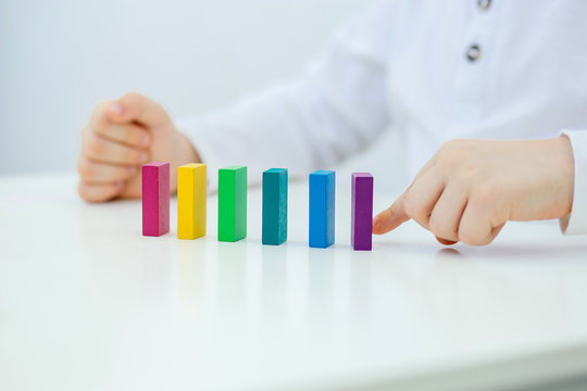 Building items in a single row. Concept of diagnostics of children's autism. A child plays with a colored wooden construction tool. Close.