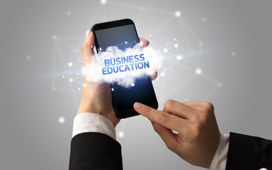 Female hand touching smartphone with BUSINESS EDUCATION inscription, cloud business concept