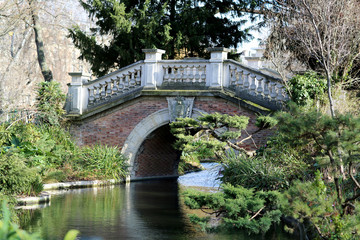 Fototapeta na wymiar Beautiful old stone bridge with railing over clean river in preserve