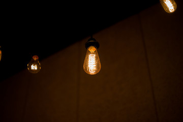 Edison lamp with warm light sways lightly on a black background