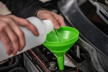 Cropped image of automobile mechanic repairing car in store,  Man or auto mechanic worker hands add distilled water to car battery. Checking and maintenance service the car battery. - 335617800