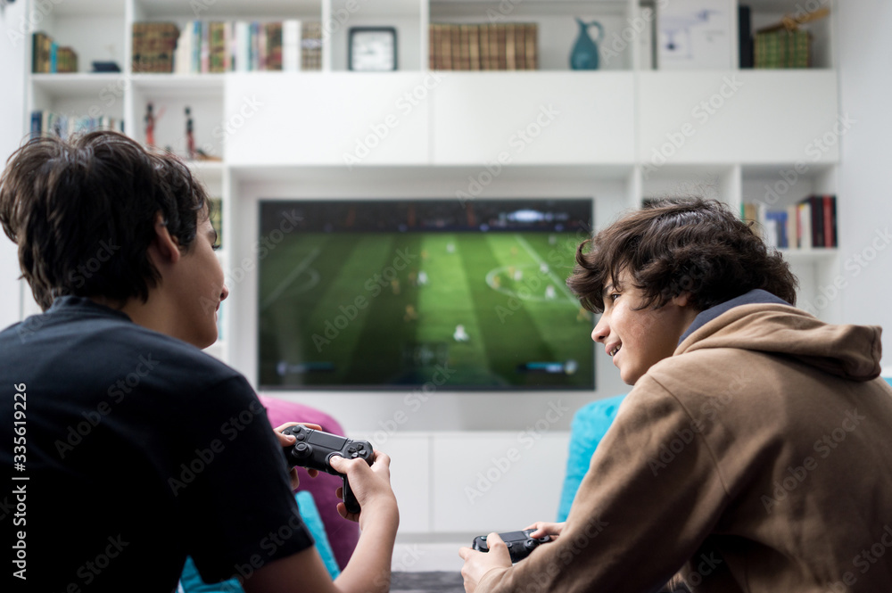 Wall mural two boys sitting at home playing video games on game console