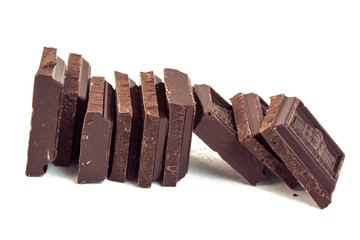 squares of dark brown chocolate stand in a row one after the other