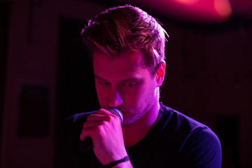 Young handsome guy emotionally sings and speaks into the microphone