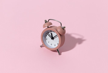 Pink alarm clock on pastel color paper background with copy space