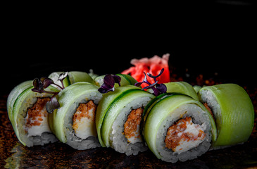 sushi roll with tuna, cucumber, cream cheese, rice in plate on black wooden table background