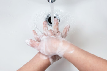 Washing hands with soap under the faucet with water
