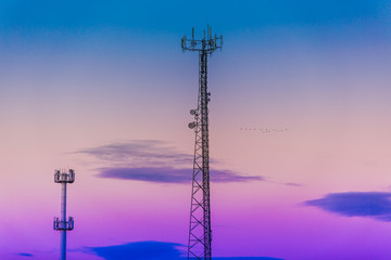 Obraz premium Silhouette in a pair of large transmission towers at sunset