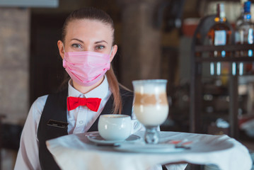 the waiter works in a restaurant in a medical mask.