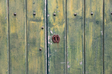 Green, wooden, vintage background with keyhole. 