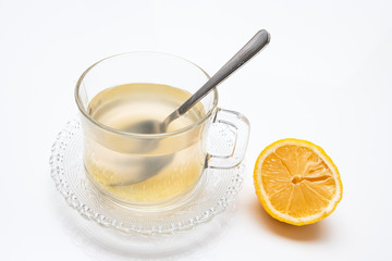 Glass cup of hot ginger tea with ginger rhizome (root) sliced and lemon, isolated on white background.