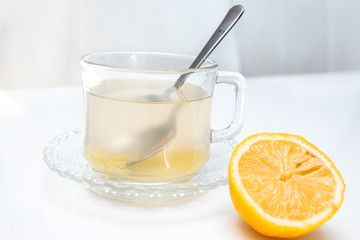 Glass cup of hot ginger tea with ginger rhizome (root) sliced and lemon, isolated on white background.