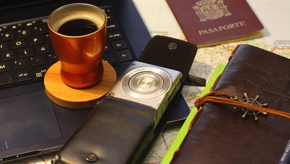 concepto de viaje con ordenador portátil, bloc de notas antiguo, cámara de fotos, café, pasaporte y de fondo un mapa de carreteras